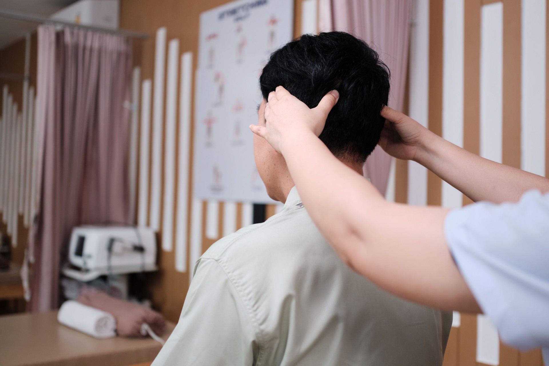 Asian mature man patient is being head massaged by physical therapist.